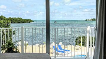 Un balcon avec vue sur la mer, une piscine et des chaises longues sur la plage.