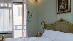 Ett hotellrum med en stor säng, ett nattduksbord, en lampa och en tavla på väggen.