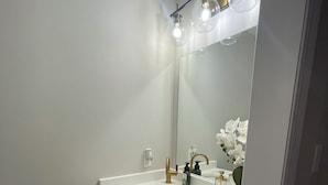 A modern bathroom with a white sink, gold faucets, and a large mirror. - Modern Townhouse, 5 Mins From all Amenities. (Guelph)