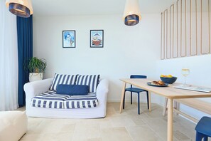 Una sala moderna con un sofá a rayas, una mesa de comedor con sillas y una planta en maceta.