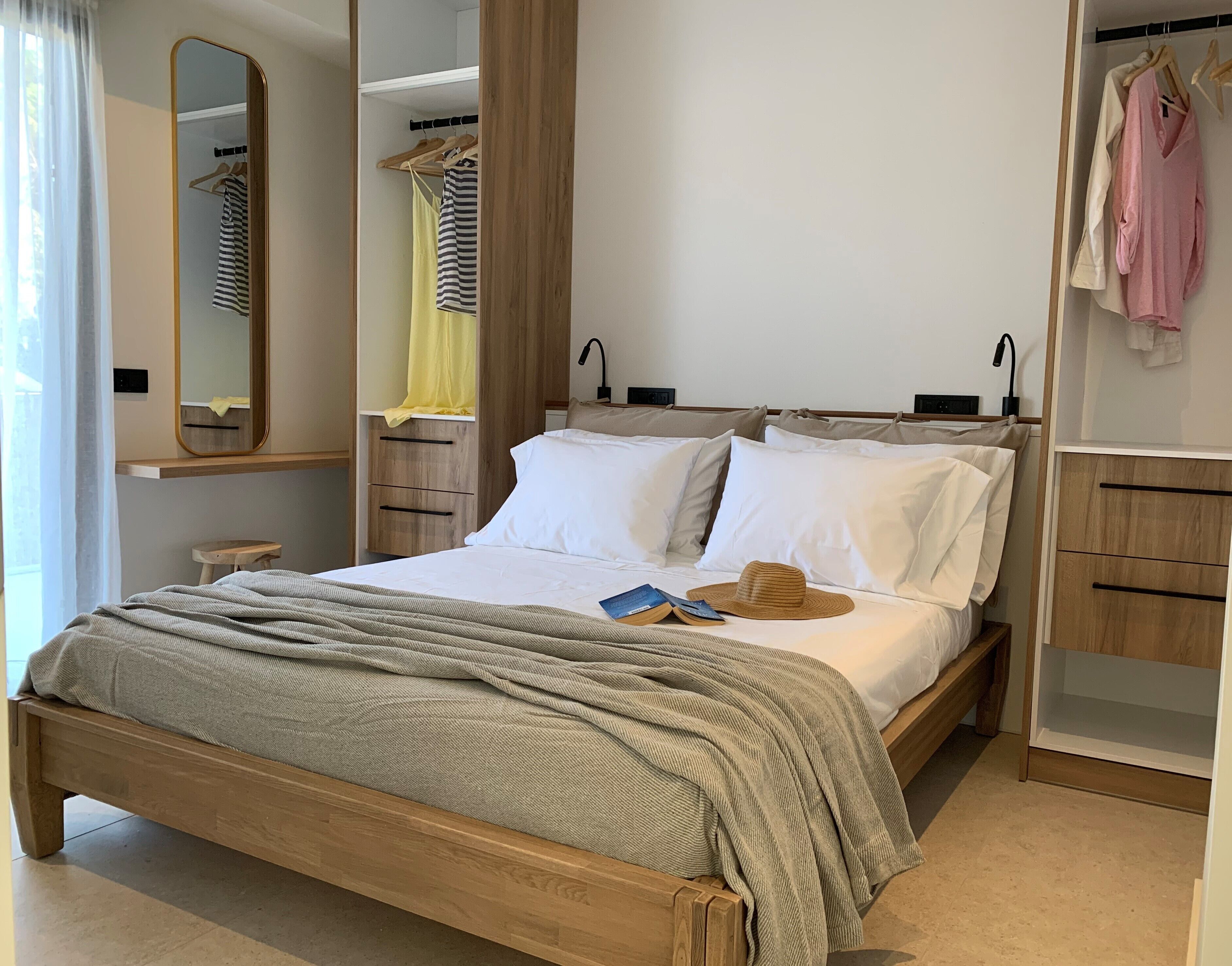 Un dormitorio ordenado con una cama de madera, una mesita de noche, un espejo y un armario.