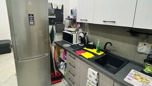Eine moderne Küche mit einem Edelstahl-Kühlschrank, einem schwarzen Spülbecken und einer Arbeitsfläche mit verschiedenen Geräten und Gegenständen.