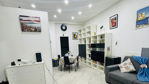 Ein modernes Wohnzimmer mit einer Couch, einer Essecke mit Tisch und Stühlen sowie einem weißen Schrank.