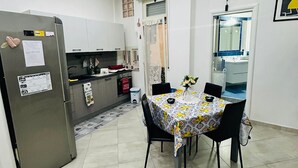 Eine kleine Küche mit Esstisch, Stühlen und einem Kühlschrank.