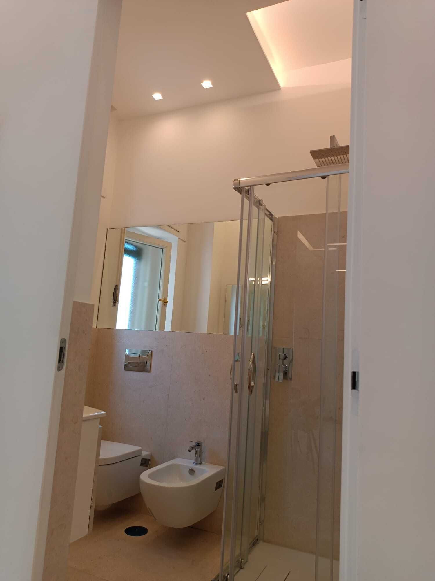 A modern bathroom with a glass shower enclosure, a bidet, and a toilet.
