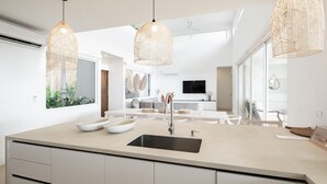 A modern kitchen with a large island, pendant lights, and a view into the dining area. - 5BR home|Mar Vista|Ocean View, Pool, Deck|Fire Pit – Casa Ayla A (Playa Flamingo)
