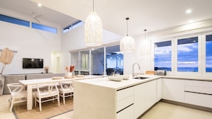 A modern kitchen with a central island, pendant lights, and a view of the sea. - 5BR home|Mar Vista|Ocean View, Pool, Deck|Fire Pit – Casa Ayla A (Playa Flamingo)