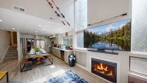 Una sala de estar moderna con chimenea, televisor grande y vistas panorámicas a un lago.