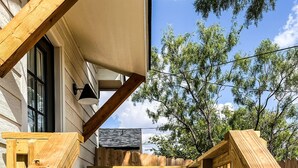 A wooden deck with a built-in seating area featuring two white chairs and a small table. - Upscale studio with skyline view (Abilene)
