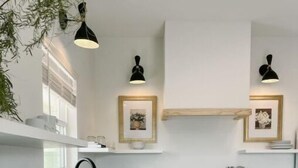 A modern kitchen with white cabinets, granite countertops, and black pendant lights. - Upscale studio with skyline view (Abilene)