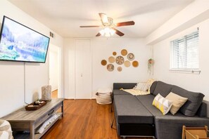 Relax in this stylish living room with a flat-screen TV, ceiling fan, and comfortable sofa.