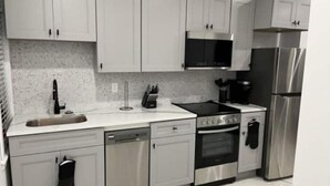 A modern kitchen with white cabinets, stainless steel appliances, a dishwasher, and a microwave.