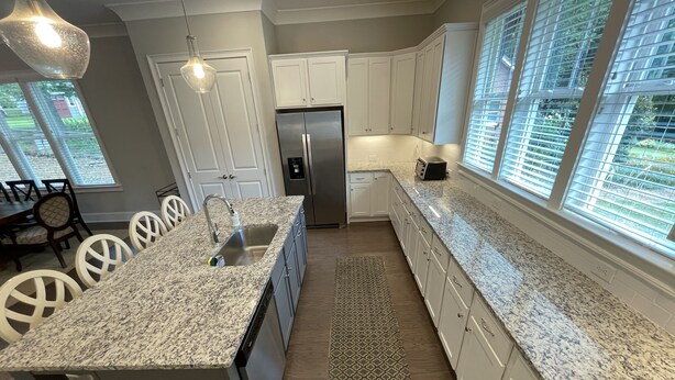 A modern kitchen with granite countertops, stainless steel appliances, and white cabinetry.