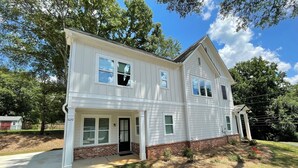 A two-story white house with a brick foundation, a front porch, and a garage.