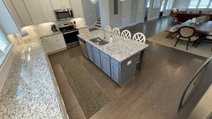 A spacious kitchen with granite countertops, a central island, and a dining area with a wooden table and chairs.