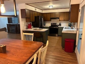A compact kitchen with dark wooden cabinets, a central island, and a red trash bin.