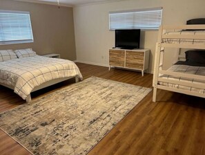 A bedroom with a bed, a TV on a wooden cabinet, a bunk bed, and a rug.