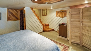 Une chambre à coucher avec un lit, un escalier en bois, une armoire et un petit bureau.