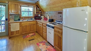 Une cuisine avec des meubles de rangement en bois, un réfrigérateur blanc, une cuisinière et un four à micro-ondes.
