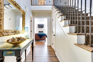 Staircase leads to a cozy space with a large mirror, wooden table, and comfortable seating area.