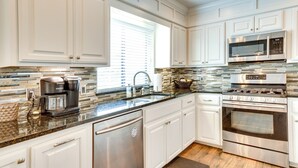 A modern kitchen with white cabinetry, stainless steel appliances, a coffee maker, and a tiled backsplash. - < 1 Mi to OU Campus - Norman Vacation Rental (Norman)