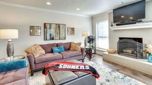 A living room with a sofa, a television, a fireplace, and decorative items. - < 1 Mi to OU Campus - Norman Vacation Rental (Norman)