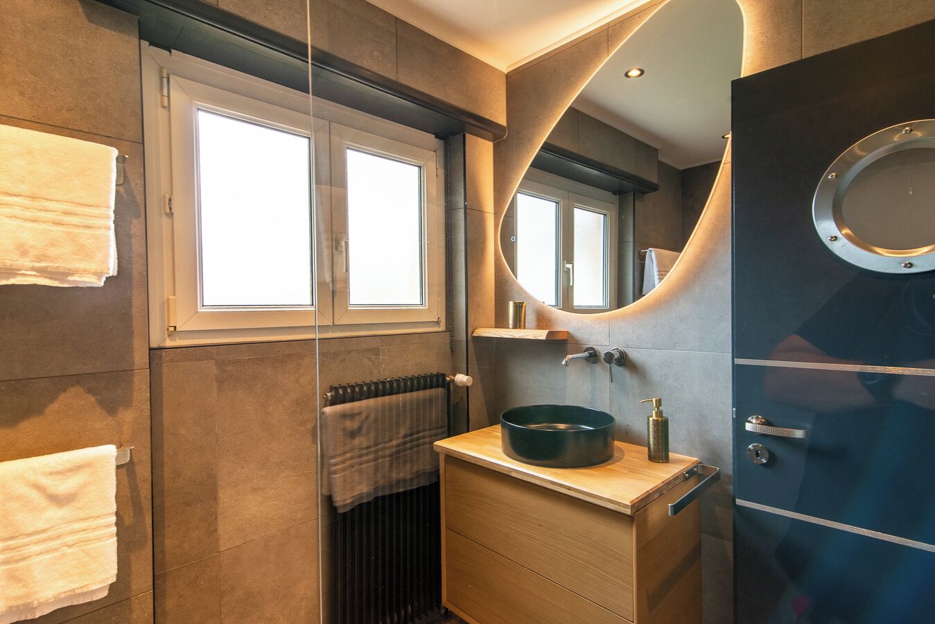 Un bagno moderno con un grande specchio, un lavandino tondo e un porta asciugamani.