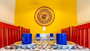 A dining area with a geometric-patterned table, blue cups, and a decorative wall piece. - Caravelas (Marechal Deodoro)
