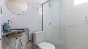 Un baño con lavamanos, inodoro y ducha con mampara de vidrio.
