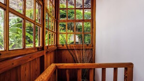 A wooden staircase with a railing, leading to a room with large windows offering a view of lush greenery outside. - Casa Yeyo, Lomo Bermejo (Santa Cruz de Tenerife)