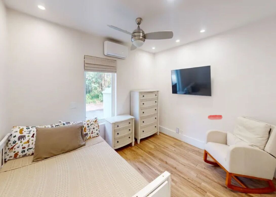 A bedroom with a bed, a dresser, a chair, a TV, and a ceiling fan.
