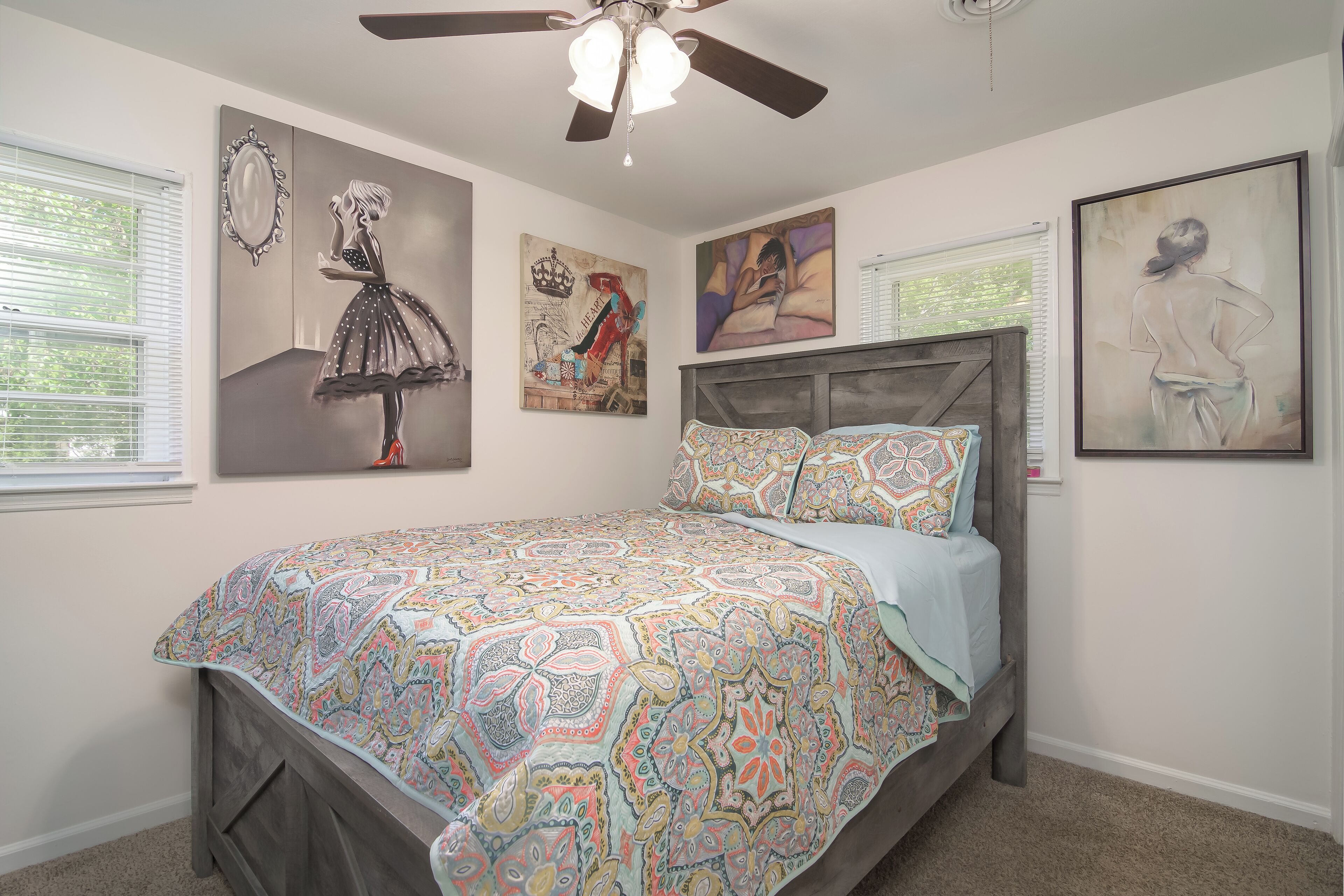 Un dormitorio con cama, ventilador de techo y decoración en la pared.