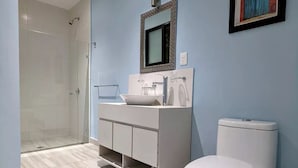 Moderni kylpyhuone, jossa on suihkukaappi, valkoinen allaskaappi peilillä ja wc.
