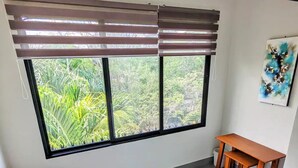 A room with a large window, a small table, and a chair.