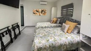 Ein Schlafzimmer mit zwei Betten, einem an der Wand befestigten Fernseher und einem Kleiderschrank.