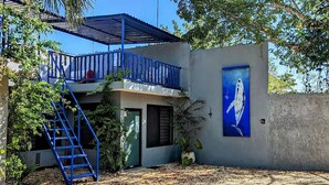 A building with a blue balcony, a satellite dish, and a painting of a bird on the wall. - The Blue Eco Lodge- double room 3 (Yalcón)
