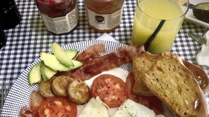 A breakfast plate with bacon, eggs, mushrooms, tomatoes, and toast on a checkered tablecloth. - The Blue Eco Lodge- double room 3 (Yalcón)