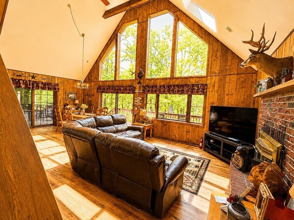A spacious loft with a large leather sofa, a television, and a deer head decoration.