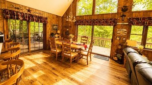 Un interior de madera con comedor, ventanas amplias y vistas a la vegetación.