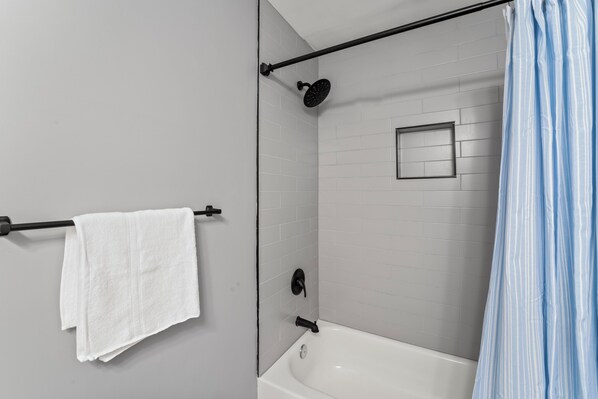 A modern bathroom with a bathtub, a showerhead, and a towel rack.