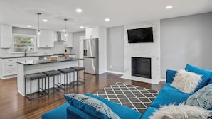 A modern kitchen with white cabinets, a central island with bar stools, a stainless steel refrigerator, and a built-in oven. - Sleek & Affordable 3 Bedroom/2 Bath in downtown Overland Park! (Overland Park)