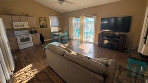 A spacious living area with a sofa, a dining table with chairs, a kitchen with a microwave, and a TV. - Palm Coast Cozy apartment<br> (Palm Coast)