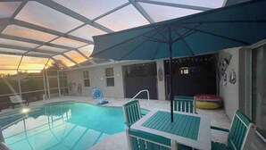 An indoor swimming pool with a glass ceiling, green chairs, and a table. - Palm Coast Cozy apartment<br> (Palm Coast)