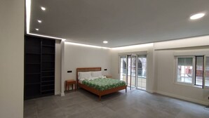Une chambre à coucher comprenant un lit, une table de chevet, un placard intégré et une porte-fenêtre coulissante donnant sur l’extérieur.