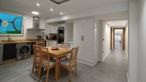 A modern kitchen with a dining area, a washing machine, and a large painting on the wall.