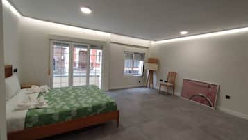 Un dormitorio con cama, una silla, una lámpara y un ventanal grande.