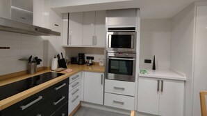 A modern kitchen with white cabinets, a black countertop, a built-in microwave, and a stove.