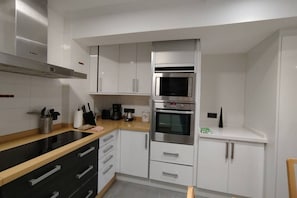 Une cuisine moderne avec des meubles blancs, un plan de travail noir, un four à micro-ondes encastré et une cuisinière.