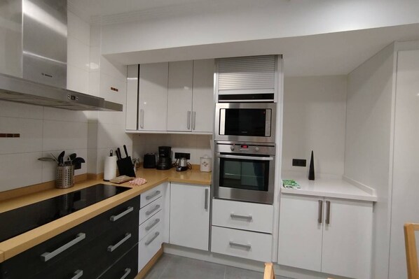 A modern kitchen with white cabinets, a black countertop, a built-in microwave, and a stove.