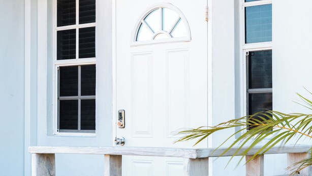 A white door with a window above it, a small porch with a railing, and a plant to the right. - The Barnyard is a chic, cozy open concept studio apartment.  (Sion Hill)